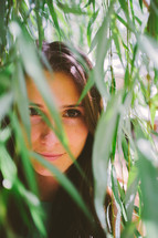 teen girl looking through bamboo leaves 