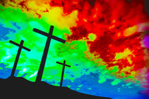 three crosses against a rainbow sky