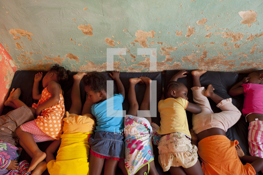 African children napping on a mat.