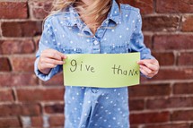 a young woman holding a give thanks sign 
