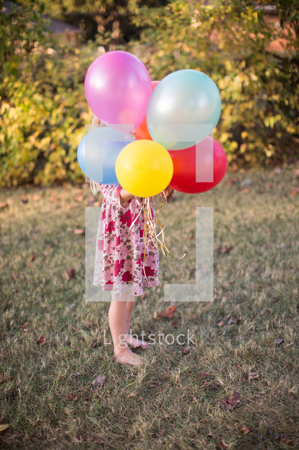 a girl child holding balloons 