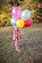 a girl child holding balloons 