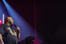 an African American man on stage holding a microphone 
