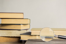 magnifying glass and a stack of books 