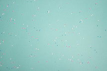 Turquoise background with pink, blue, and white confetti