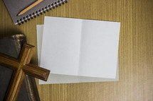 white papers, journal, and cross on a desk 