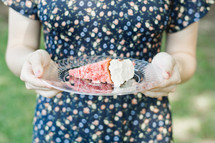 a woman holding a slice of cake on a plate 