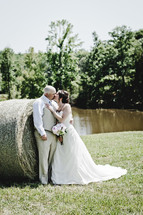 a bride and groom kissing by a hay bale 