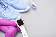 women's sneakers, pink weights, and smartwatch 