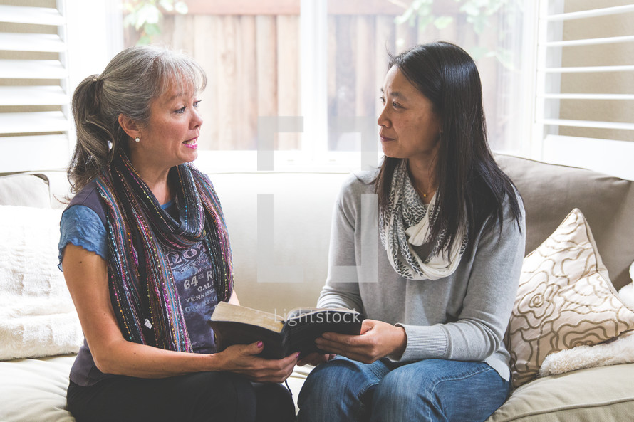 Asian women siting on a couch reading a Bible 