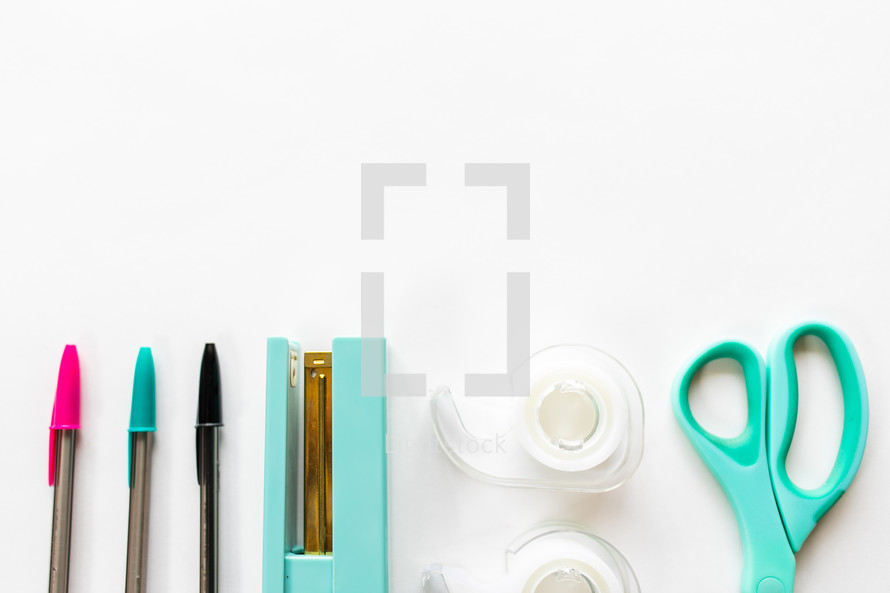 pens, stapler, tape, and scissors on a white background 