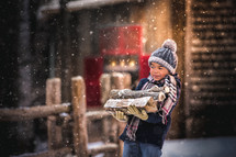 a boy carrying firewood in the snow 
