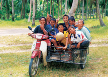 Eight kids in on a motorbike and side car carriage 