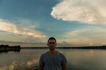 man standing in front of a lake at sunset 
