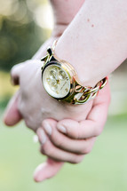 Two hands clasped together and a watch on one wrist.