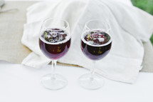 Two glasses of red wine on white napkins.