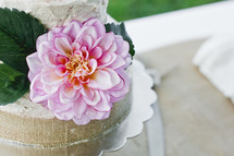 pink flower and burlap around a wedding cake 