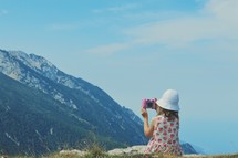 a girl taking a picture of a mountain 
