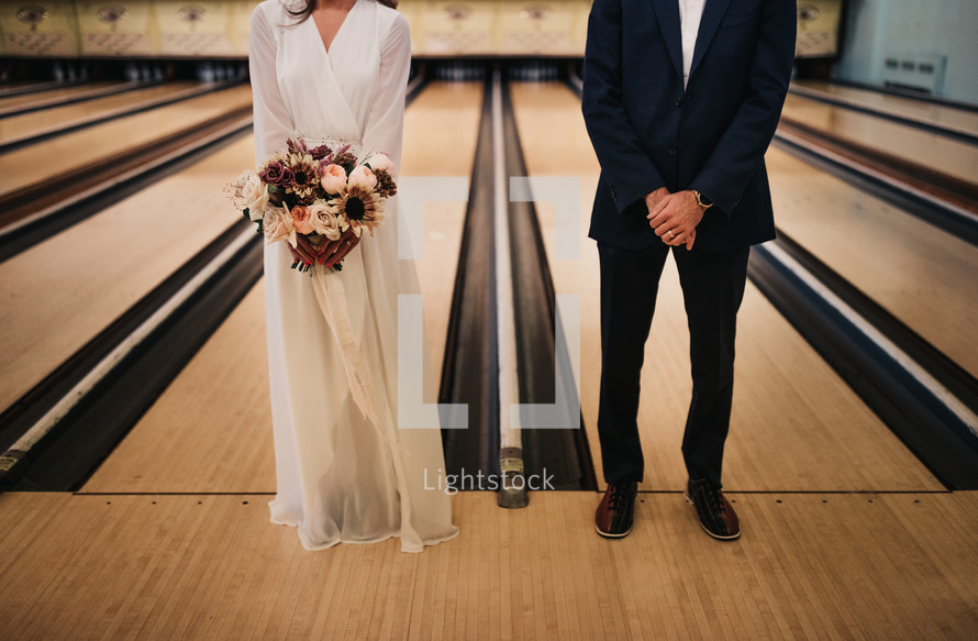 bride and groom standing in a bowling alley 