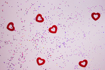 red hearts and glitter on a pink background 