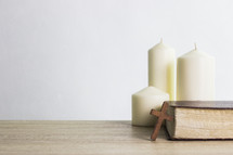 three white candles, Bible, and cross