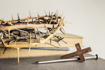 nail, cross, and crown of thorns next to books 