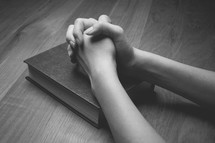 praying hands over a Bible 