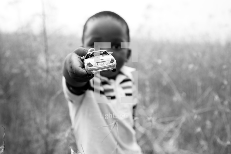 little boy holding out a toy car