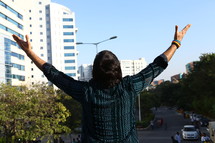 man with arms raised in a city