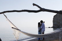 a hammock on a beach and a couple hugging 