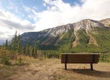 A wooden bench facing a mountain.