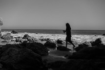 woman walking onto a rocky beach 