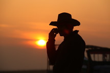 silhouette of a cowboy on a cellphone at sunset 