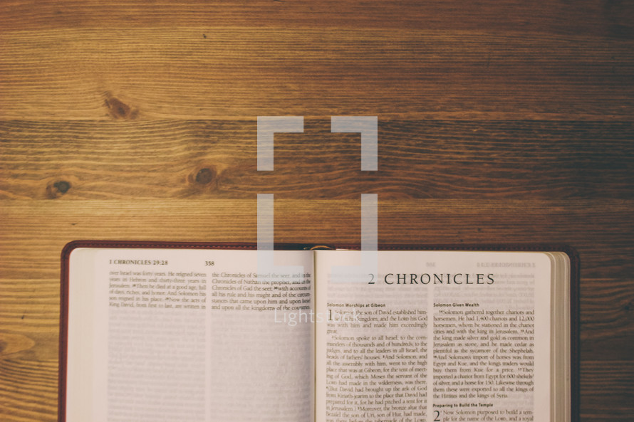 Bible on a wooden table open to the book of 2 Chronicles.