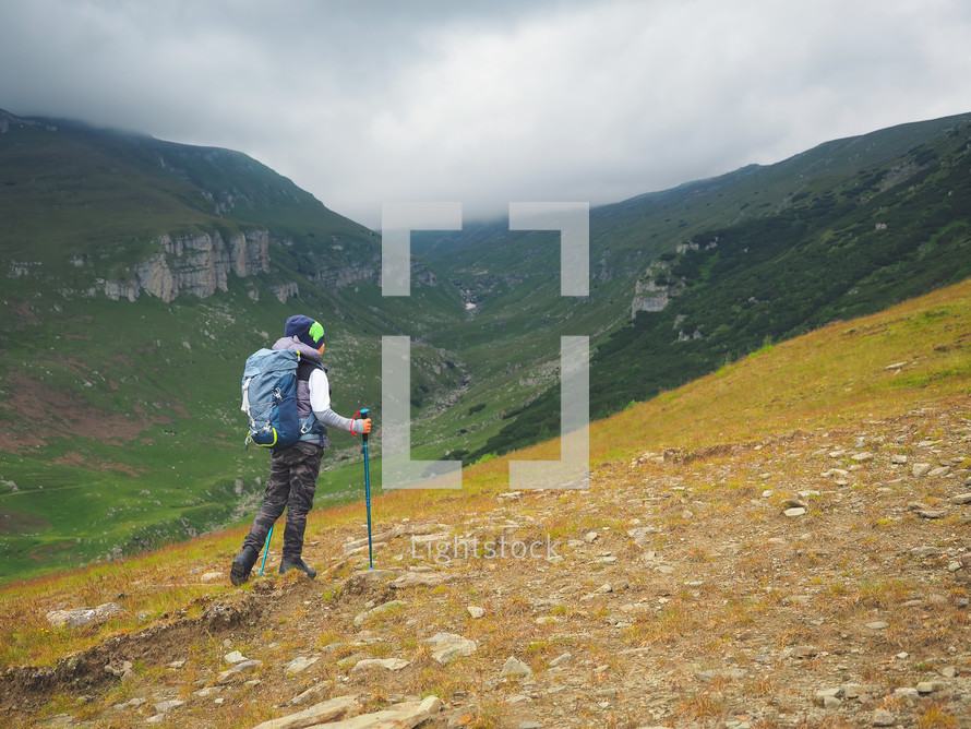 Little boy with backpack hiking in scenic mountains