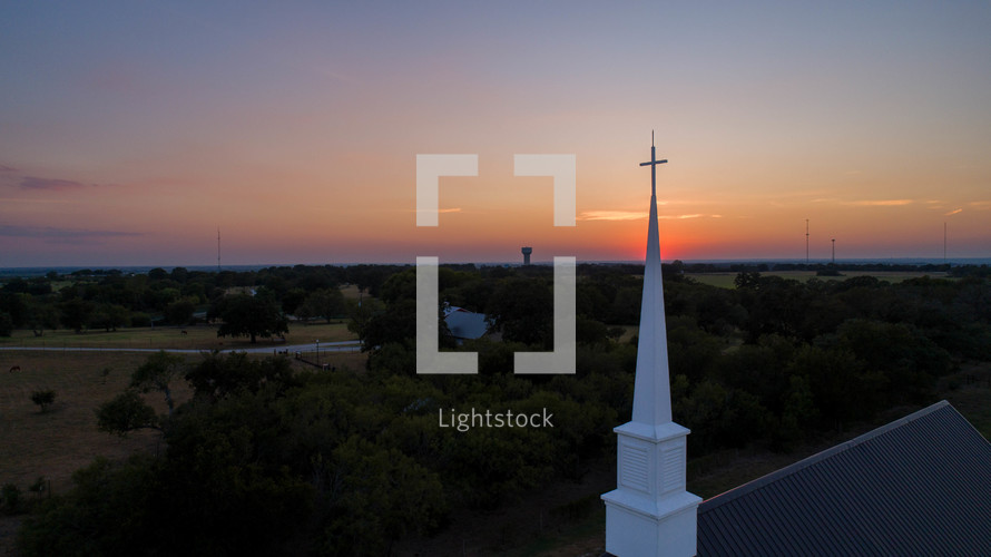 Traditional church steeple in the countryside at sunset.