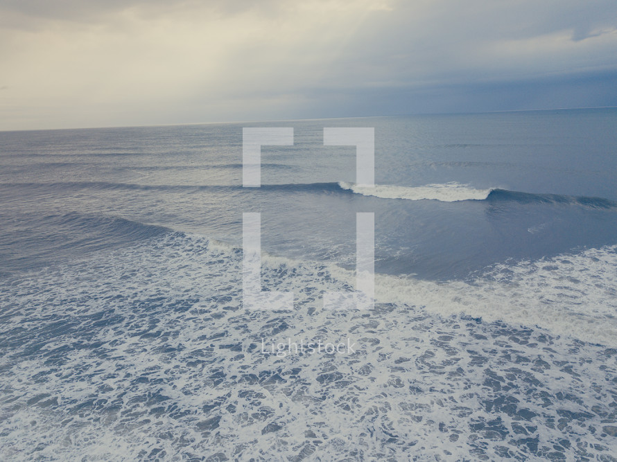 Drone image of the ocean while a wave is crashing.