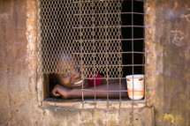 face of a child through a barred window 