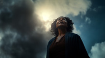 Older black woman looking up at the sky with a serious expression. 