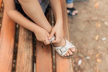 girl fastening her sandals 