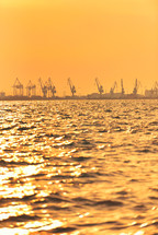 Heavy industrial port equipment, big cranes in sunset light