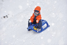 child sledding in snow 