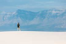 A girl alone in the sandy desert looking out at the mountains