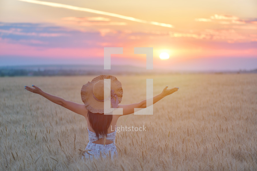 a woman standing in a golden wheat field 