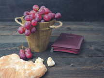 breaking bread, with wine, grapes and Bible in the background