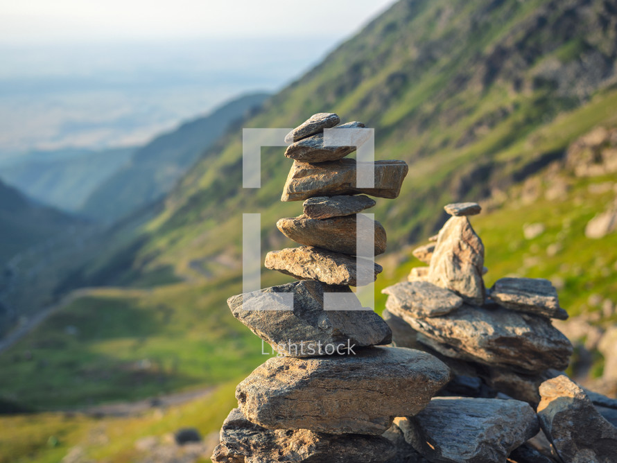 Stone stack with balanced stones on blurred mountain background in sunset warm light