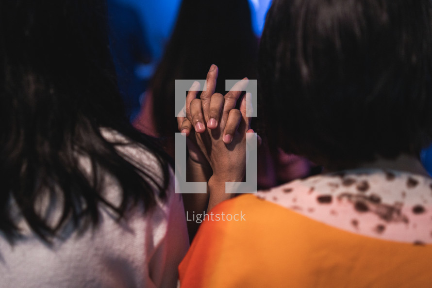women holding hands during a worship service 
