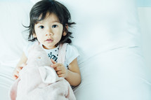 toddler girl lying on a bed 