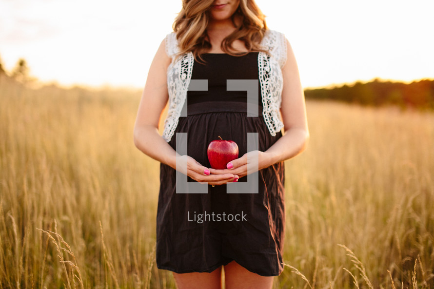 woman standing in a field cradling an apple