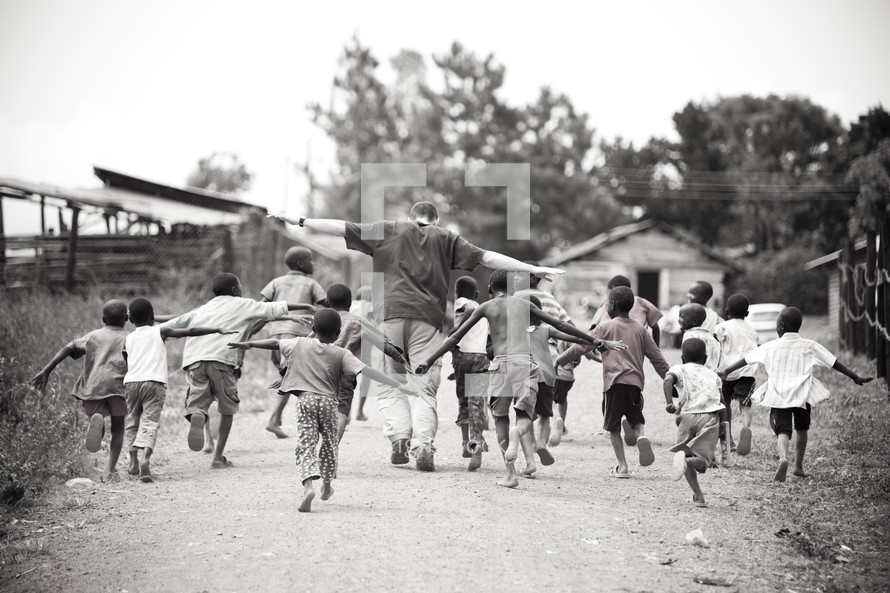 Man running with children on a dirt road
